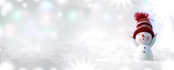 Christmas background. Happy snowman standing in a winter Christmas landscape. Merry christmas and happy new year greeting card. Funny snowman in a hat on a snowy background. Banner.