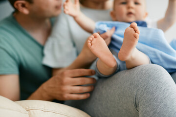 Obraz na płótnie Canvas Close-up of baby and his parents enjoy in time together at home. Focus is on baby's feet.