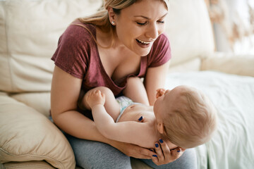 Happy mother enjoys with her baby son at home.