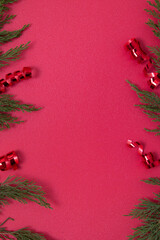 Christmas red background with decorative elements and green branches flat lay