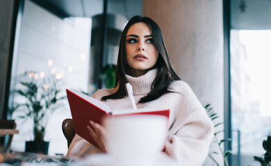 Thoughtful woman with notebook in cafe