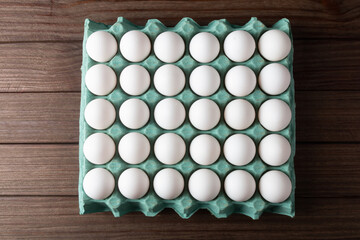 Carton of fresh eggs isolated on wooden background.