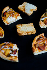 some slices of pizza and toast white bread arranged abstract. the western food isolated on black.