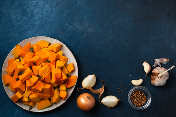 Sliced pumpkin and other ingredients for pumpkin cream soup on blue background top view