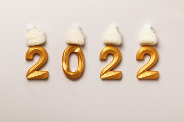 New Year inscription 2022 numbers in gold color in knitted hats on a white background.