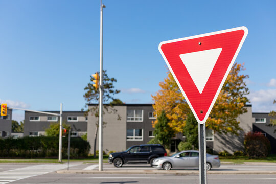 Yield give way road traffic sign on street with cars driving in Ottawa, Canada in fall