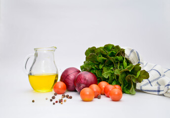 a bunch of green salad, tomatoes, olive oil, ed onion on the wite background. Ingridients for salad.