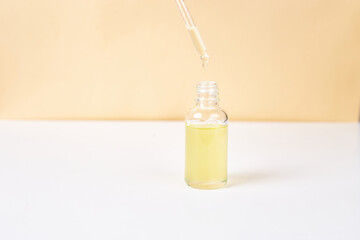 Pipette with essential oil over bottle on white and yellow background. Natural medicine concept. Aromatherapy