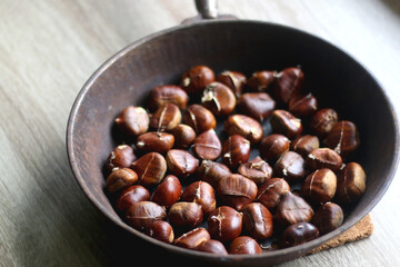 Cast iron pan filled with chestnuts. Selective focus.