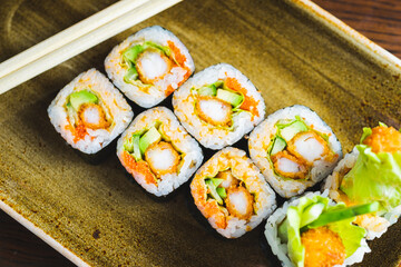 Traditional Japanese rolls with shrimps and vegetables on a plate with wooden chopsticks