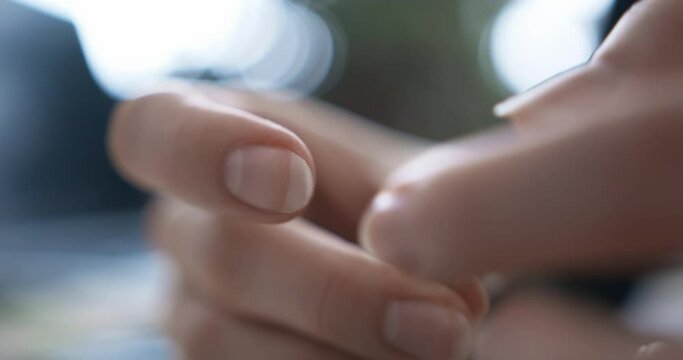 A woman is threading a green thread through the eye of a needle. Close-up. Needlework.