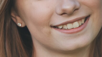 A young girl smiles and shows her crooked teeth.