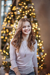 Portrait of a smiling girl on the background of a New Year tree at Christmas