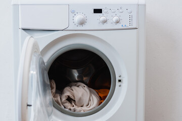 laundry in open washing machine near white wall.