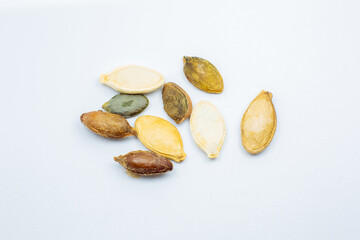 Different colorful  Dry Roasted Pumpkin seeds on white background. Tasty and healthy food. Close up photo.