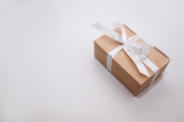 craft gift box tied with a white satin ribbon on a white background with a place for signature