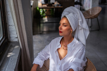 Beautiful woman portrait while wearing red lipstick and turban towel on head while daydreaming in...