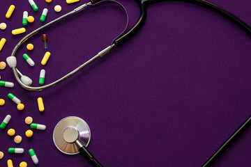 Medical pills, tonometer and stethoscope on the Purple surface. Blood pressure measurement. Color capsules medication. Health care concept. Medicines. Many different pills. Chemical industry.