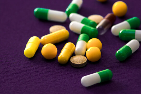 Medical pills. Color capsules medication. Purple background. Health care concept. Free space for text. Medicines. Many different pills. Chemical industry.