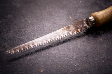 Old vintage wood hacksaw on a dark background