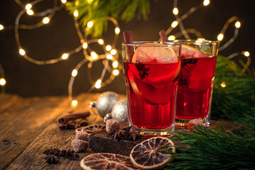 Mulled wine on the background of burning lights, fir branches and toys.
