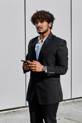 Businessman is standing on the street and looking at his phone