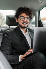 Indian businessman in the backseat with laptop