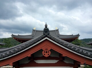Roof of old Japanese temple decorated with dragon face on cloudy sky. Culture, history, travel