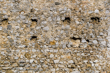 Medieval wall with holes on wooden beams that fell out of time