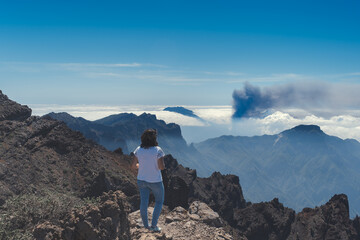 A woman looks at Cumbre Vieja eruption from the top of Caldera de Taburiente. La Palma. Canary Islands