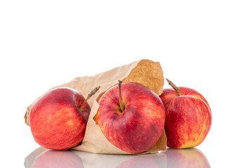 Three juicy red apples with a paper bag, close-up isolated on white.