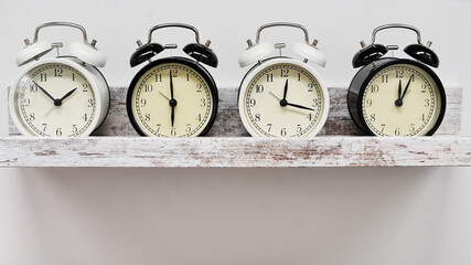 Row of vintage alarm clocks on a shelve, white background. Time management concept 