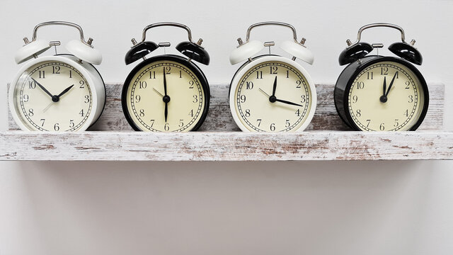 Row Of Vintage Alarm Clocks On A Shelve, White Background. Time Management Concept 