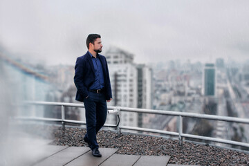 Businessman on the top of building and looking at foggy city 