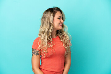 Fototapeta premium Young Brazilian woman isolated on blue background looking to the side and smiling