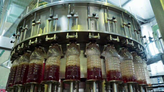Plastic bottles getting filled with red drink