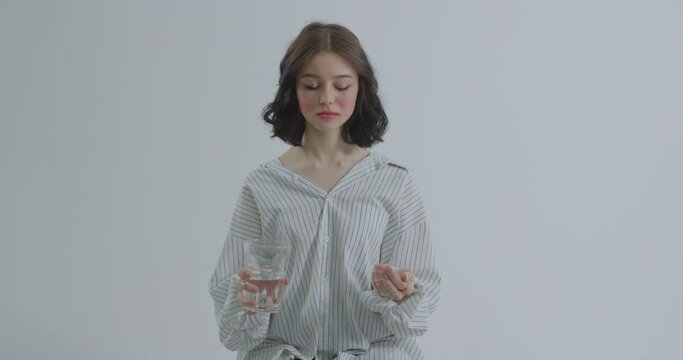 A teenager who wants to commit suicide with the help of pills. The girl is crying holding a pill and a glass of water.