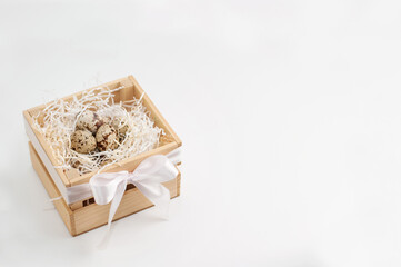 quail eggs in paper filling in a wooden box on a white background