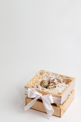 quail eggs in paper filling in a wooden box on a white background