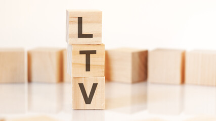 wooden cubes with letters LTV arranged in a vertical pyramid, on the light background, reflection surface, concept.