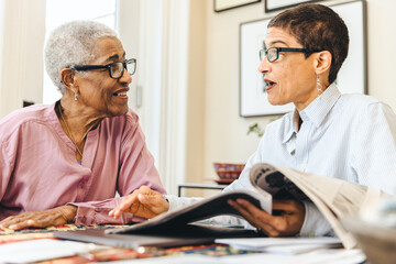 Elderly black woman sits in conversation with her adult daughter at home 
