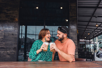 Obraz premium Beauty couple drinking smoothie on cafe hipster style, beard man, woman in the dress, happy face, love romantic,Couple having coffee at a coffee shop. Man and woman meeting at cafe,Attractive smiling
