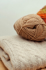 Knitting, tangles yarn, needles and ready-made knitted products. Vertical photography.