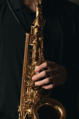 saxophonist with a beautiful wind musical instrument, musician plays the saxophone, hands close-up, jazz and blues background