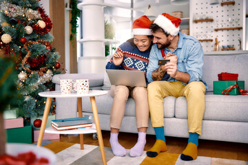 Fototapeta premium Young couple shopping online with credit card at home for Christmas