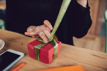 Unrecognizable person opening present in cozy cafe