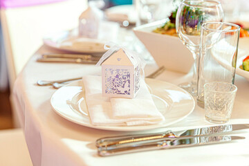 Fancy table set for dinner with napkin glasses in restaurant, luxury interior background. Wedding elegant banquet decoration and items for food arranged by catering service on white tablecloth table.