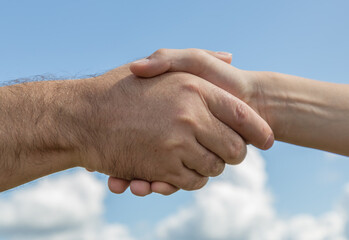 Handshake of an adult and a young man against the blue sky . the concept of supporting the transfer of experience