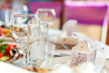Fancy table set for dinner with napkin glasses in restaurant, luxury interior background. Wedding elegant banquet decoration and items for food arranged by catering service on white tablecloth table.