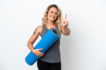 Young sport Brazilian woman going to yoga classes while holding a mat isolated on white background smiling and showing victory sign